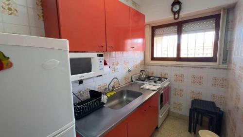 cocina con armarios rojos, fregadero y nevera en Edificio Natania, en Villa Gesell