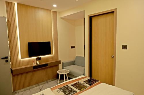 a hotel room with a bed and a chair and a television at Hotel VD Rooms in Surat