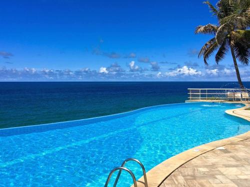 a swimming pool with the ocean in the background at Mercure Salvador Rio Vermelho in Salvador