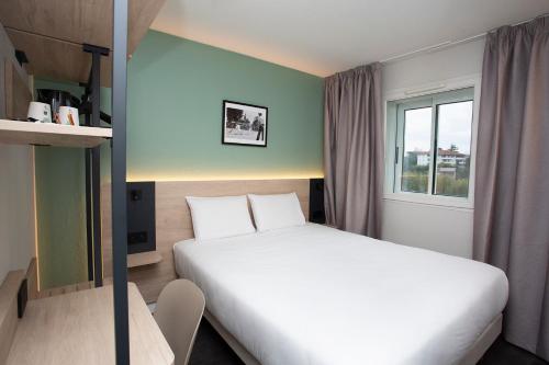 a small bedroom with a bed and a window at Kyriad Anglet - Biarritz in Anglet