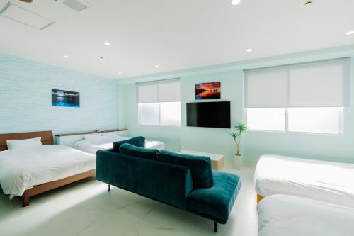 a bedroom with two beds and a couch and a tv at Sea Side Gaia Resort HOTEL シーサイドガイアリゾートホテル in Sendai