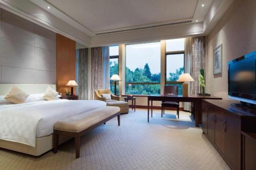 a bedroom with a bed and a desk and a television at Suzhou Jinji Lake Grand Hotel in Suzhou