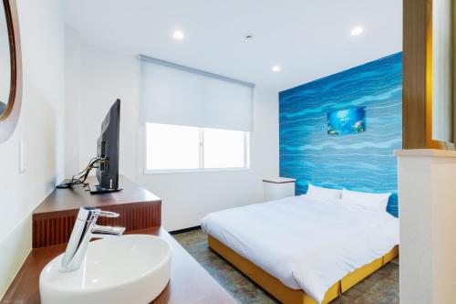 a bedroom with a bed and a sink and a television at Sea Side Gaia Resort HOTEL シーサイドガイアリゾートホテル in Sendai