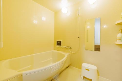 a white bathroom with a tub and a mirror at Sea Side Gaia Resort HOTEL シーサイドガイアリゾートホテル in Sendai