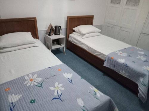 een slaapkamer met 2 bedden met bloemen op de deken bij Javoxir Guest House in Samarkand