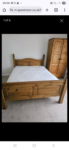 a bedroom with a wooden bed with white sheets at 14 london road in Stonewood