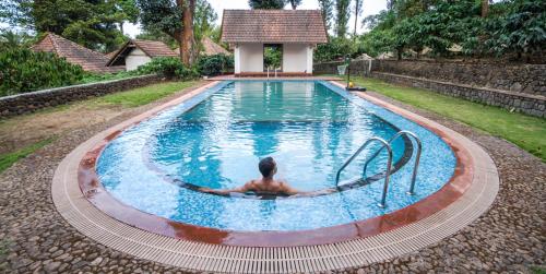 a man in a swimming pool with a person in it at Misty Woods Resort in Kakkabe