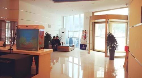 7 Days Inn Korla Passenger Station في Bayingholin: غرفة بها تلفزيون على طاولة في مبنى