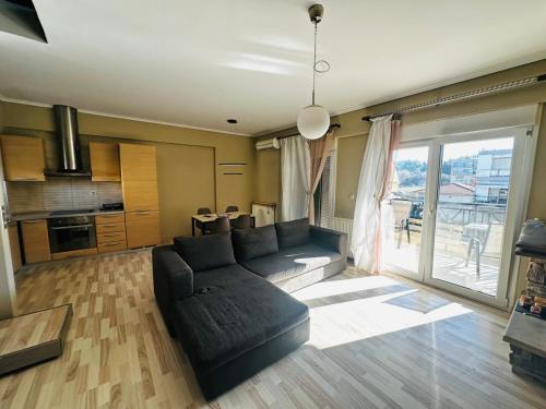 a living room with a black couch and a kitchen at JD Maisonette for 4 in Neoi Epivates