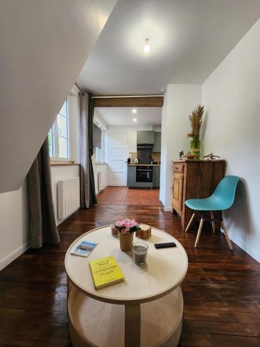 Una sala de estar con una mesa y una cocina. en Séjour idyllique normand - Appartement cosy à 5 min de la plage - Veules-les-Roses, en Veules-les-Roses