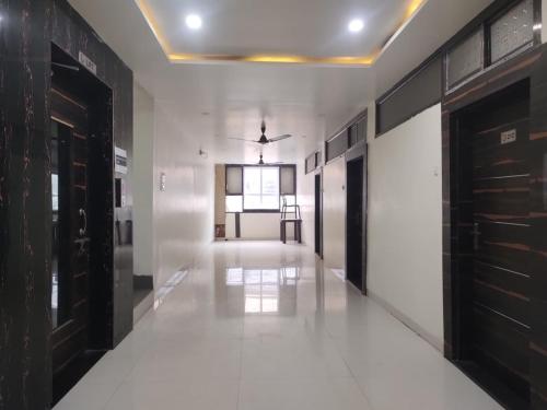 um corredor com piso branco e portas pretas em Hotel Suryadeo em Jabalpur