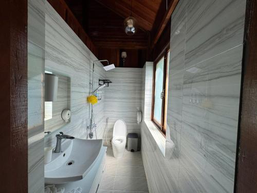 a white bathroom with a sink and a toilet at Cat Tien Vista in Tân Phú
