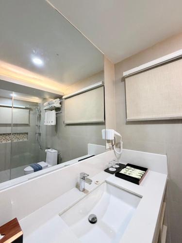 a white bathroom with a sink and a shower at Solina Beach & Nature Resort in Carles