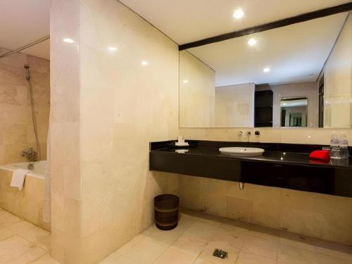 a bathroom with a sink and a tub and a mirror at Hotel Horison Sagita Balikpapan in Klandasan Kecil