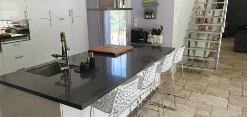 BELLE VILLA 8 à 10 personnes parc du verdon في La Verdière: مطبخ بأعلى كونتر أسود ودواليب بيضاء