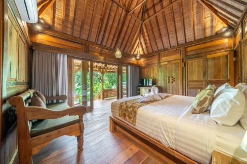 a bedroom with a large bed and a wooden ceiling at Saughina Ubud in Ubud