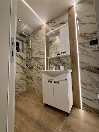 a bathroom with a white sink and marble walls at Apartman Andrijana in Bajina Bašta