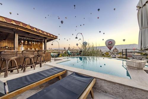 a resort with a pool and a bar and hot air balloons at Cappadocia Inn Cave Hotel in Göreme