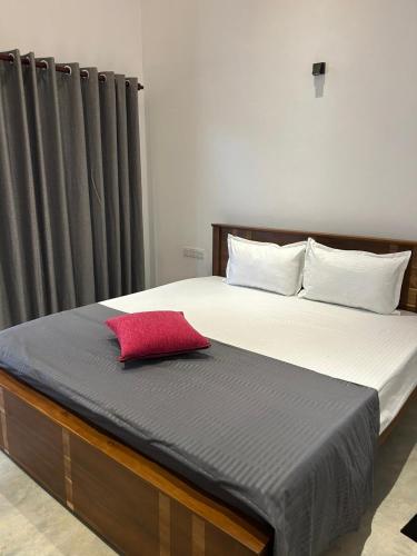 a bed with a red pillow on top of it at Costal View-Ahangama in Ahangama