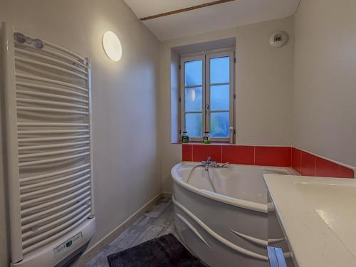 a white bathroom with a tub and a window at La Rose Urban avec Parking privé et Gare à 2 min in Nogent-le-Rotrou