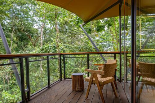 a screened in porch with two chairs and a table at Tifakara by the Waterfall in Fortuna