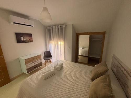 a bedroom with a white bed and a mirror at Duplex entre molinos Consuegra in Consuegra