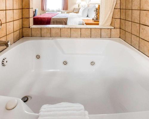 a white bath tub in a bathroom with a bedroom at Quality Inn Sidney in Sidney