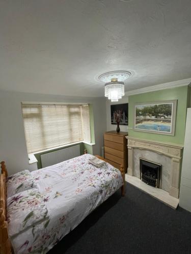 a bedroom with a bed and a fireplace at Lovely 4 bed house with patio & bbq in Slades Green