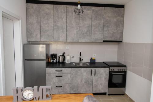 Una cocina con frigorífico de acero inoxidable y fregadero. en Apartmani Loznica Premia, en Loznica