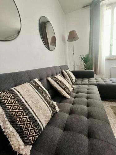 a gray couch with pillows in a living room at Le Nid De Demolombe in Caen