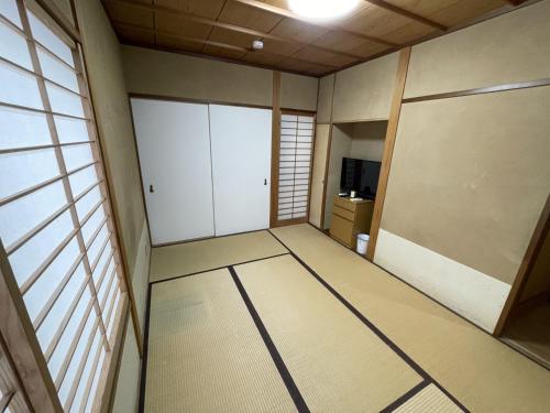 an empty room with white closets and a television at 伊東駅前ゲストハウス in Ito