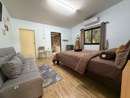 a bedroom with a bed and a couch and a window at Krabi Bloom House in Ban Khlong Khamao (2)