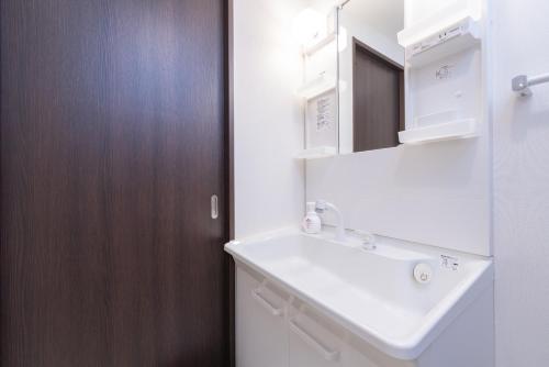 a bathroom with a sink and a wooden door at Nagoya Sta 14 min Up to 7 2 Beds and Sofa Bed in Nagoya