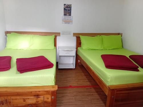 T Bungalow في نوارا إليا: سريرين في غرفة ذات أغطية خضراء وأحمر