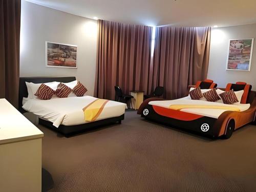 two beds in a hotel room with a car bed at Paragon City Hotel in Kampong Simee