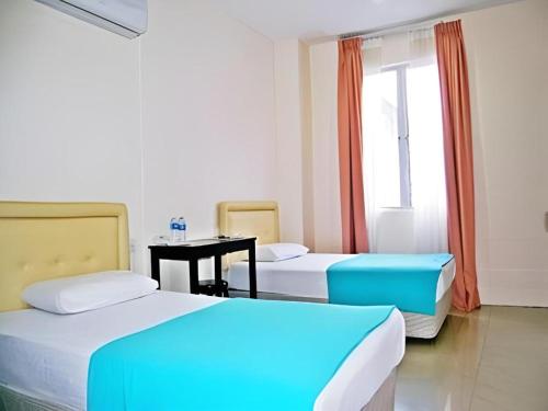 a room with two beds and a table and a window at Rafayeh Hotel in Kampong Lobok