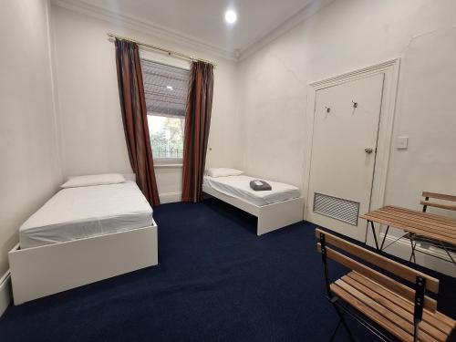 a small room with two beds and a window at Adelaide Free Souls in Adelaide