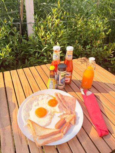 une assiette d'œufs et de pain grillé sur une table en bois dans l'établissement LeLaNa Farmstay Camping, à Pak Chong