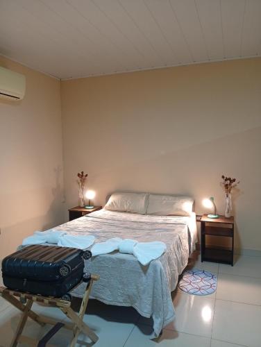 een slaapkamer met een bed en een stoel met een koffer bij Marias Alojamiento in Garupá