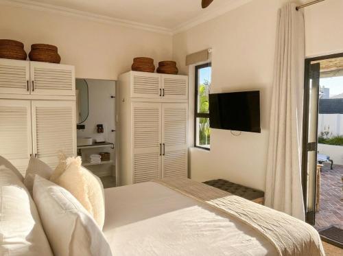 a bedroom with a bed and a tv on the wall at Ibis Cottage Hout Bay with Mountain View Terrace in Hout Bay