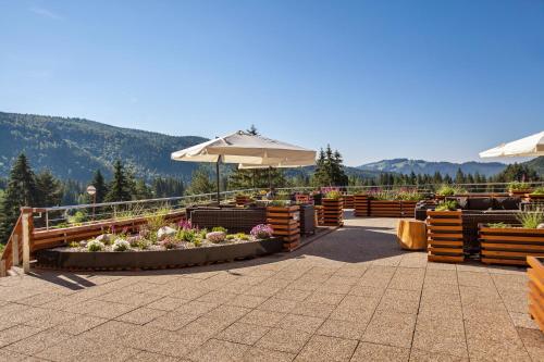a patio with tables and umbrellas and flowers at Hotel Partizán in Tale