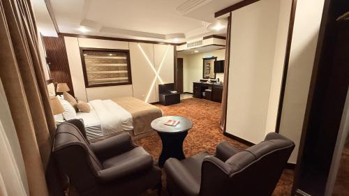 a hotel room with a bed and chairs and a mirror at Rojina Hotel in Amman