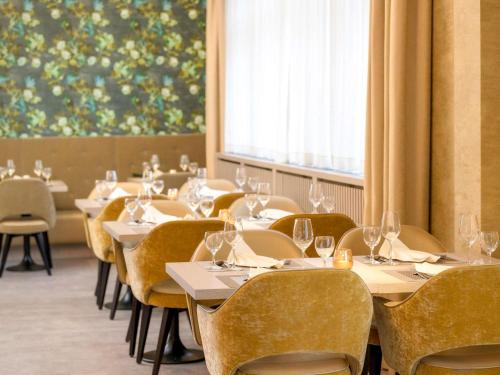 ein Esszimmer mit Tischen und Stühlen und einem großen Fenster in der Unterkunft Mercure Hannover Oldenburger Allee in Hannover
