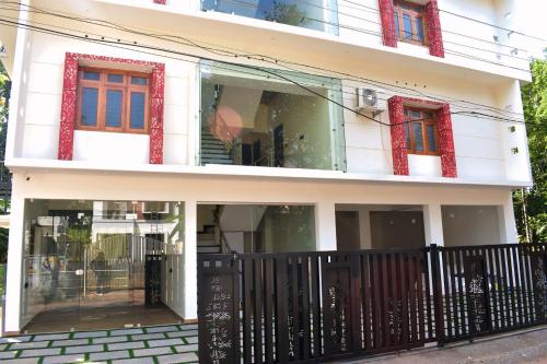 una casa blanca con ventanas rojas y una valla negra en De Waves, en Varkala