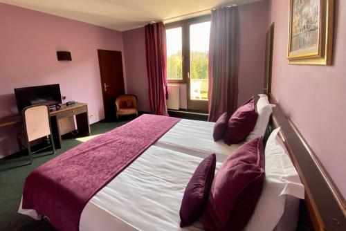 a bedroom with a bed and a desk and a window at Hôtel Des Vosges in La Celle-sous-Gouzon