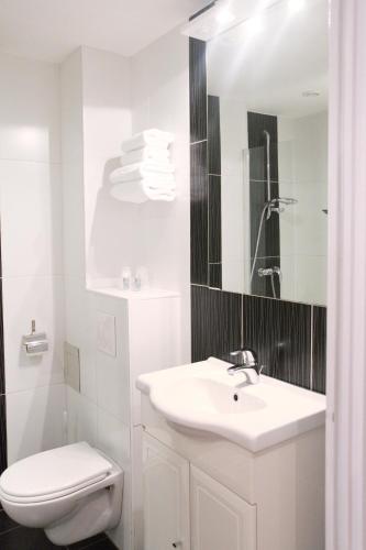 a white bathroom with a sink and a toilet at Hôtel Des Vosges in La Celle-sous-Gouzon