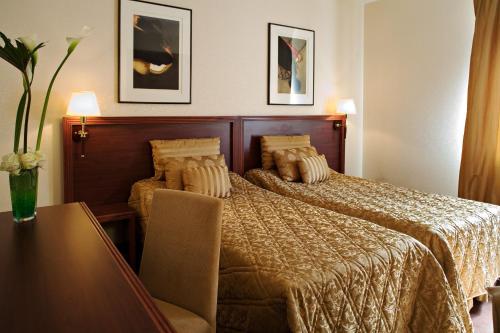 Hôtel Des Vosges في La Celle-sous-Gouzon: غرفة في الفندق مع سرير وطاولة مع منضدة sidx