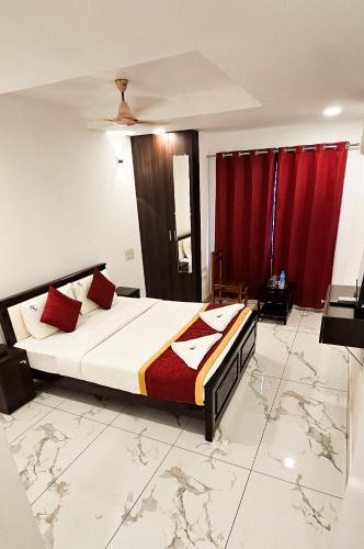 a bedroom with a large bed with red curtains at SAADHANA COMFORTS LODGE in Udupi