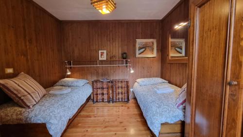 twee bedden in een kamer met houten wanden bij Antica Dimora Dolomiti in Vodo Cadore