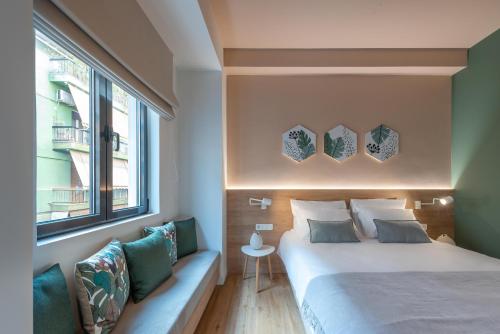a bedroom with a bed and a couch and a window at Corto Maltese Boutique in Athens